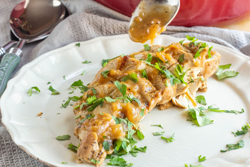 Honey apple braised chicken plated with sauce and cilantro